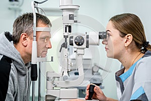 Optometrist examining the eyes of a male patient in a modern ophthalmology clinic. Eye doctor with man patient during an