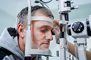 Optometrist examining the eyes of a male patient in a modern ophthalmology clinic. Eye doctor with man patient during an