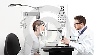 Optometrist examining eyesight patient in optician office on wh