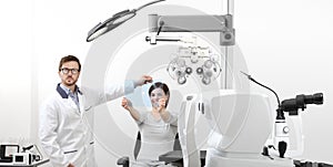 optometrist examining eyesight woman patient pointing at the hole on plexiglass in optician office, ocular dominance test photo