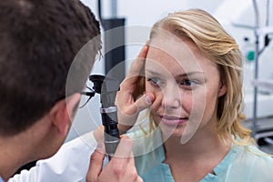 Optometrist examining female patient through ophthalmoscope