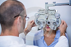 Optometrist examining female patient on phoropter