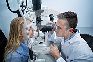 Optometrist examining female patient on slit lamp