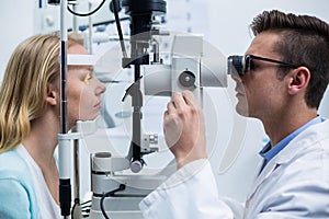 Optometrist examining female patient on slit lamp