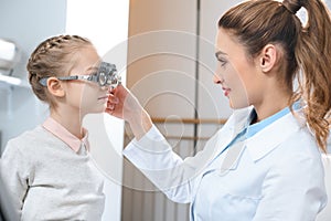 optometrist examining kid eyes with trial frame