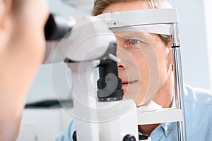 optometrist examining man with modern