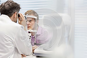 Optometrist examining patient on phoropter at hospital