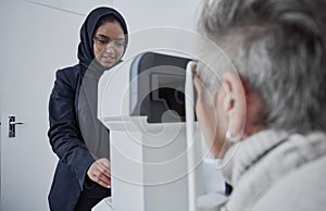Optometrist, muslim woman and testing eyesight health in optometry lab with optical machine indoors. Senior patient in