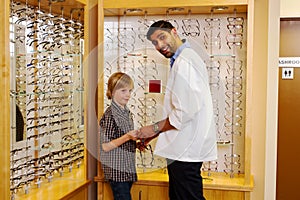 Optometrist showing glasses to young lad