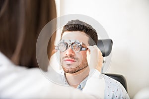 Optometrist taking eye test through trial frames at the clinic