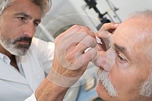 Optometrist using mydriatics eye drops to numb eyes