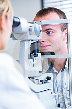 Optometry concept - handsome young man having his eyes examined