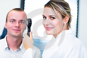 Optometry concept - handsome young man having his eyes examined photo