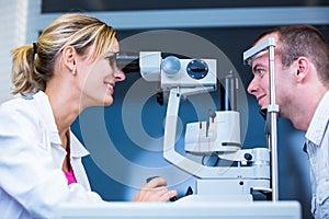 Optometry concept - handsome young man having his eyes examined photo