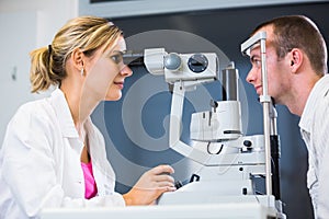 Optometry concept - handsome young man having his eyes examined photo