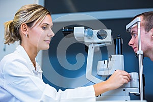 Optometry concept - handsome young man having his eyes examined photo