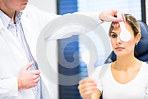 Optometry concept - pretty young woman having her eyes examined photo