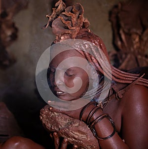 A traditional himba tribe woman doing her beauty procedure