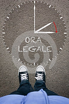 Ora Legale, Italian Daylight Saving Time on asphalt with two shoes, high angle from above photo