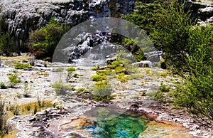 View on cascade with steaming hot clear blue alkali chloride thermal pool