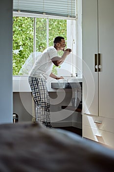 Oral care, brushing teeth and black man with dental hygiene in the bathroom of his modern home. Grooming, healthcare and