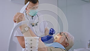 Oral care treatment for a old man patient came for a visit to the dentist he laying down on the dentist chair and have a