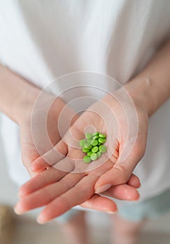 Oral contraceptives. Green pills in women`s hands close up. Protection from unwanted pregnancies