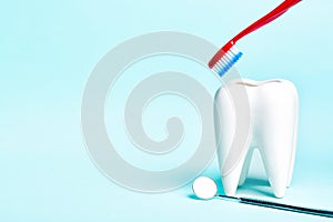 Oral dental hygiene. Dental mirror near healthy white tooth model with toothbrush on light blue background. Free space for your