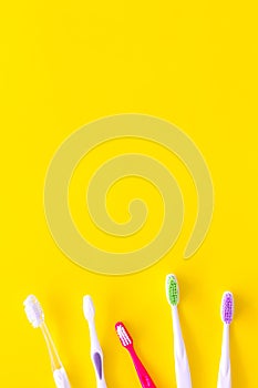 Oral hygeine. Toothbrushes on yellow background top view copy space