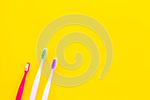 Oral hygeine. Toothbrushes on yellow background top view copy space