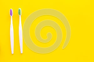 Oral hygeine. Toothbrushes on yellow background top view copy space