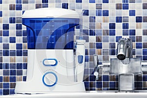 Oral hygiene, bathroom objects concept. Mouth teeth cleaning irrigator modern tool on sink.