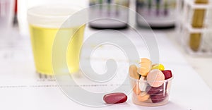 Oral pills for urinary tract infection problems, lab tests and bottles with urine collected in the background photo