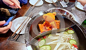 Orande melting piece of fat shaped as bear figure in steel hot dish for cooking of traditional Chinese food