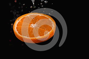 Orange slice with bubbles over on black background photo