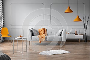 Orange accents in grey living room interior with copy space on empty wall photo