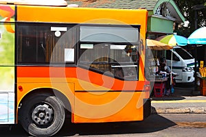 An orange air-conditioned bus parked at the bus stop in Bangkok