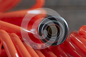 An orange air hose with an hose coupling on a black background, closeup. Detail of air compressor hose and pistol