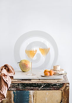 Orange Amber wine in glasses, fruits and cheese, copy space