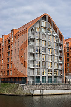 Orange apartments building in front of lake with blue sky at the background. Gdansk, Poland