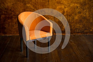 Orange armchair against the background of a brown wall. Interior