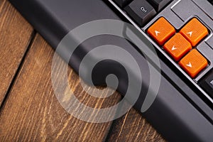 Orange arrow keys on a black keyboard, up, down, left, right buttons on a gaming computer keyboard
