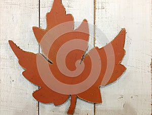 Orange artificial maple leaf on wood background