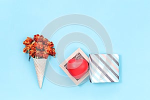 Orange autumn flowers in waffle cone with heart in hift box on light blue