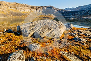 Orange autumn greenlandic  tundra landscape with big stone and lake in the background, Nuuk, Greenland photo