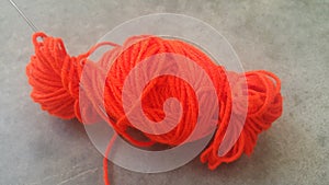 Orange ball of threads wool yarn for knitting on grey floor background