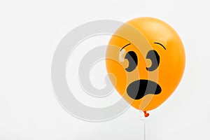 Orange balloon with drawing of scared face on background, space for text. Halloween party