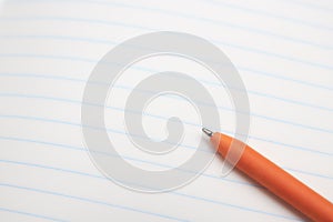 Orange ballpoint pen lies on a white sheet of paper close-up. concept of education. place for text