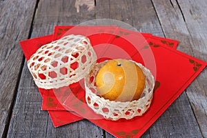 Orange in a basket on old wooden board with Chinese red envelope packet or ang pao background. Happy Chinese new year concept.