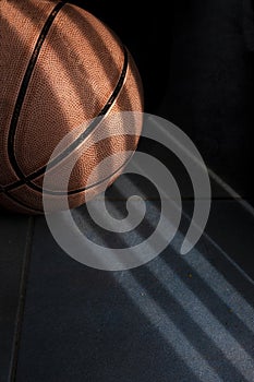 An orange basketball ball on a dark blue floor.